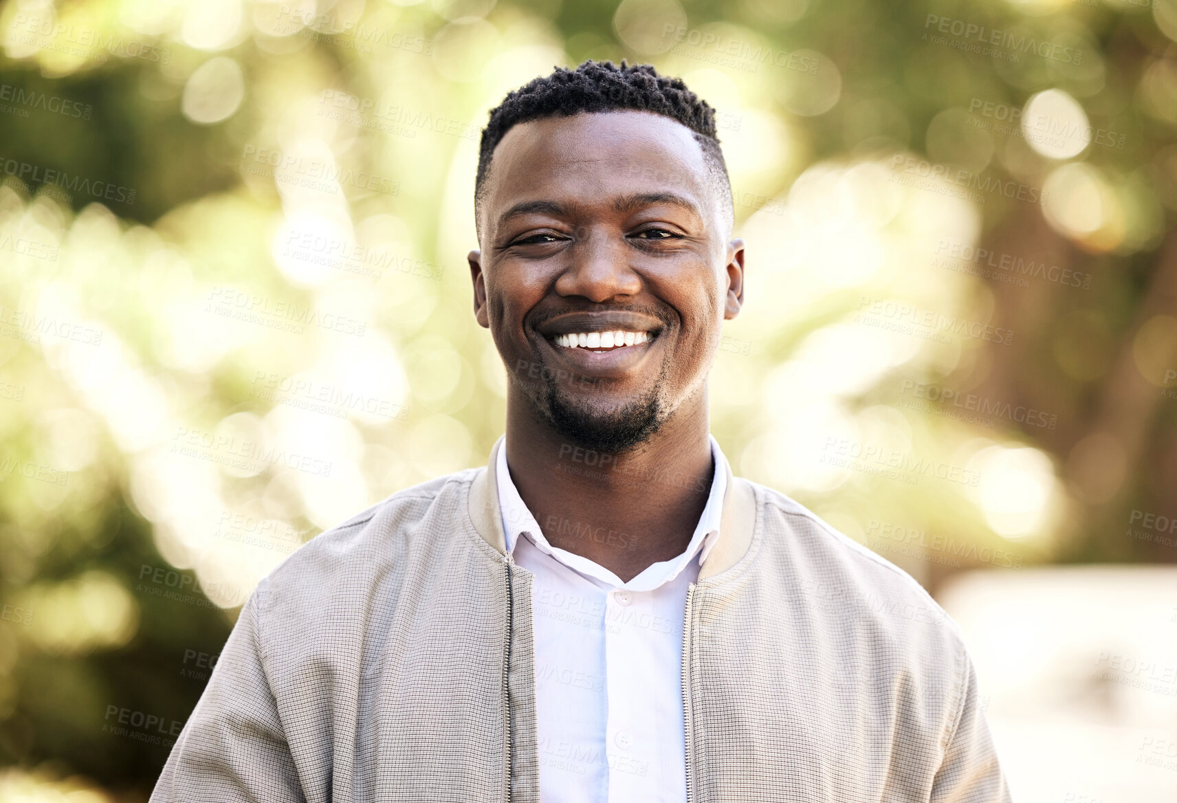 Buy stock photo Portrait of a young businessman standing in the street in the city smiling and looking happy on a sunny day. African american male expressing happiness on his face