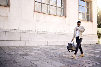 Buy stock photo Black businessman travelling alone.A african american businessman walking around town with his luggage while looking at his watch for the time