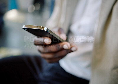 Closeup of Black businessman travelling in a train while using a cellphone. African american male using a wireless device while commuting on a train