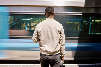 Black Black businessman travelling alone. Rear View of a african american businessman waiting for a train at a railway station during his commute at a train station travelling alone