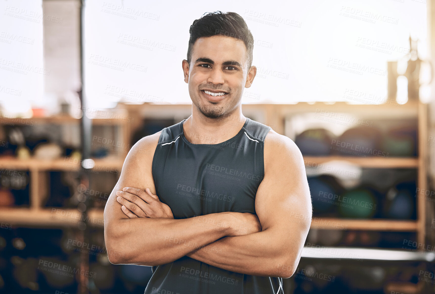Buy stock photo Proud fitness coach in his gym. Confident exercise trainer arms crossed. Happy young man standing in a gym. Bodybuilding requires confidence. Sporty, strong fitness man in the gym.