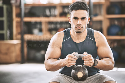 Serious trainer lifting heavy kettlebell. Bodybuilder building strong arm muscle with heavy weights. Portrait of fit young man working out in the gym. Muscular arms come from heavy weights