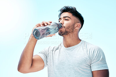 Fit young mixed race man drinking water from a bottle while exercising outdoors. Handsome hispanic male taking a sip of water during a break from his workout outside. Cardio and endurance training