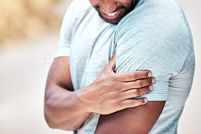 Buy stock photo Closeup fit mixed race man holding his shoulder in pain while exercising outdoors. Unrecognizable male athlete suffering with a muscle injury to his arm. Every workout comes with risk of getting hurt