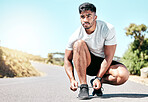 Athletic young mixed race man tying his shoelaces before a run. Handsome hispanic male athlete fastening his laces and getting ready for a run. Getting ready for some cardio and endurance training
