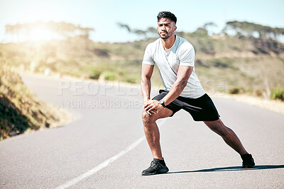 Fit young mixed race man stretching before his exercise outdoors. Handsome hispanic male warming up and getting ready in preparation for a run or jog outside in nature. Endurance and cardio training