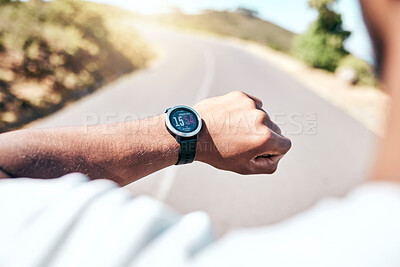 Buy stock photo Fit man timing himself during his run outdoors. Ethnic man checking his smartwatch while exercising outside