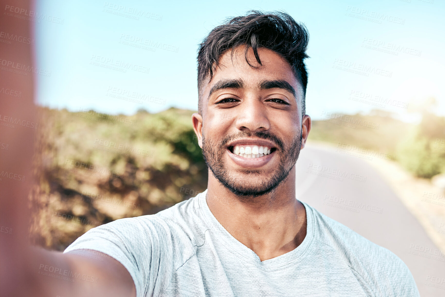 Buy stock photo Closeup fit mixed race man taking a selfie while out for a run. Handsome hispanic male athlete smiling for a self portrait photograph while exercising outdoors. Taking pictures on his fitness journey