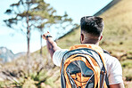 Rearview fit mixed race man pointing to his goal or destination while out for a hike. Unrecognizable male athlete gesturing towards the end or finish of his hiking journey. He has fitness aspirations