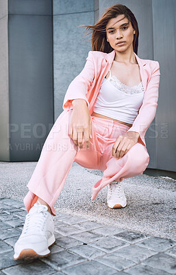 Young trendy and confident mixed race woman looking stylish while posing and spending time in the city. Fashionable young hispanic woman wearing pink clothes and enjoying time in the city
