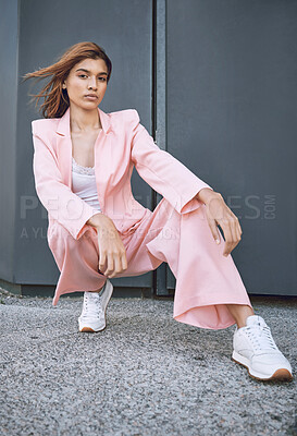 Portrait of a young trendy and confident mixed race woman looking stylish while posing and spending time in the city. Fashionable hispanic woman wearing pink clothes and enjoying time in the city