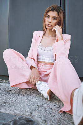 Portrait of a young trendy and confident mixed race woman looking stylish while posing and spending time in the city. Fashionable hispanic woman wearing pink clothes and chilling in the city