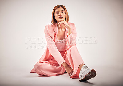 Portrait of a young mixed race female posing in trendy fashionable clothing while chilling on a floor of a studio. Hispanic woman showing the latest fashion collection with a cool style and sneakers