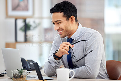 Young cheerful mixed race businessman working on a laptop alone in an office at work. One confident happy hispanic businessperson reading an email on a laptop at work