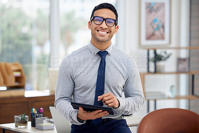 Buy stock photo Portrait of a young mixed race businessman holding and using a digital tablet standing in an office at work. One content hispanic male businessperson typing on a digital tablet at work