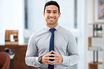 Young happy mixed race businessman standing alone in an office at work. One confident hispanic businessperson smiling while standing at work