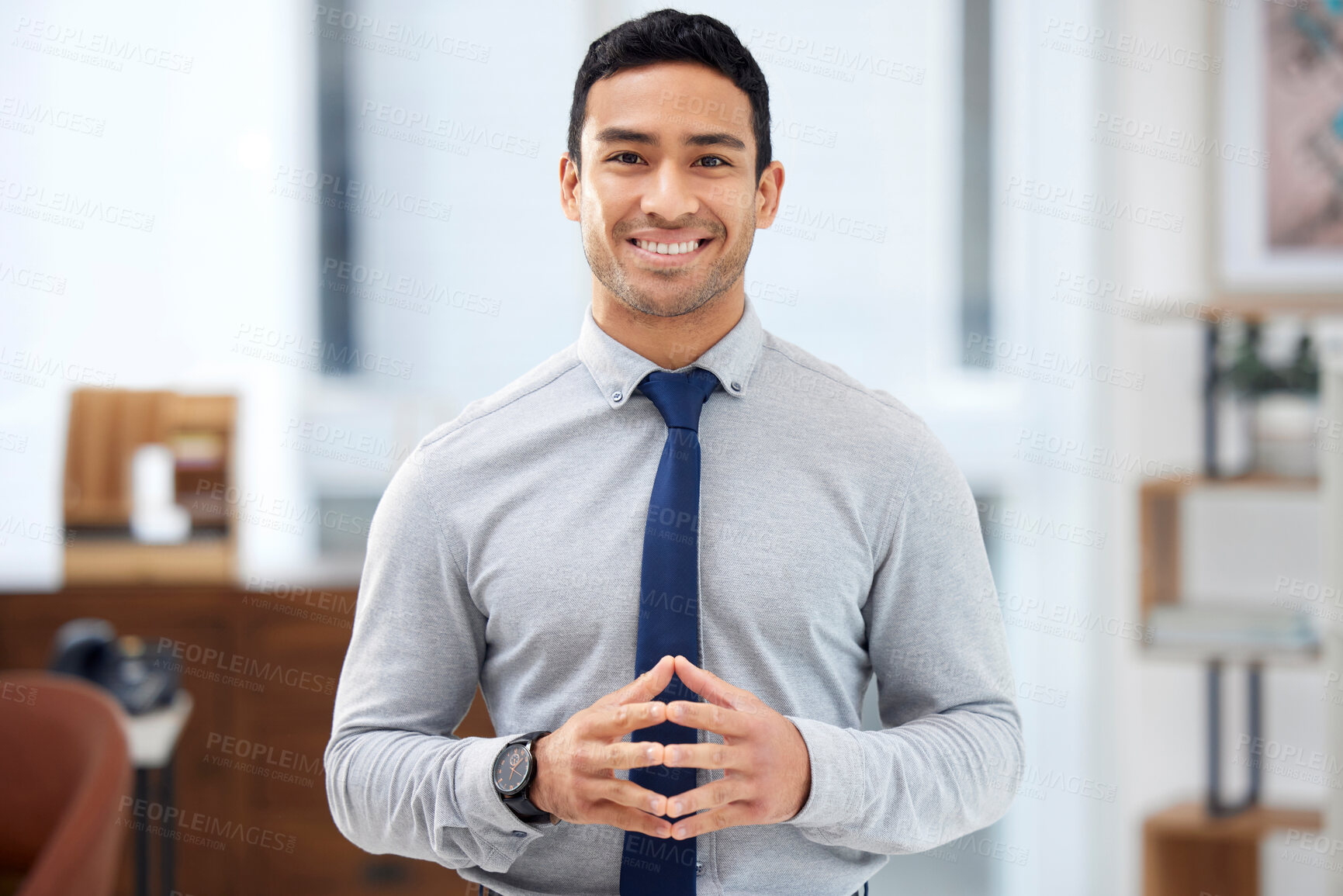 Buy stock photo Young happy mixed race businessman standing alone in an office at work. One confident hispanic businessperson smiling while standing at work