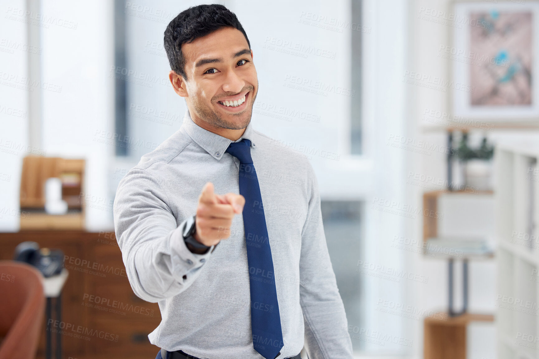 Buy stock photo Young happy mixed race businessman pointing a finger while standing alone in an office at work. One hispanic businessman standing and making a hand gesture at work