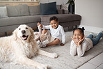 Two young mixed race siblings playing on the lounge floor with their adopted dog. Two adorable children bonding with an animal rescue at home