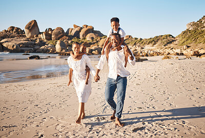 Buy stock photo Full length portrait of young african american parents holding hands while carrying their two children and taking a walk along the beach. Young family with little daughter and son spending time together and enjoying vacation