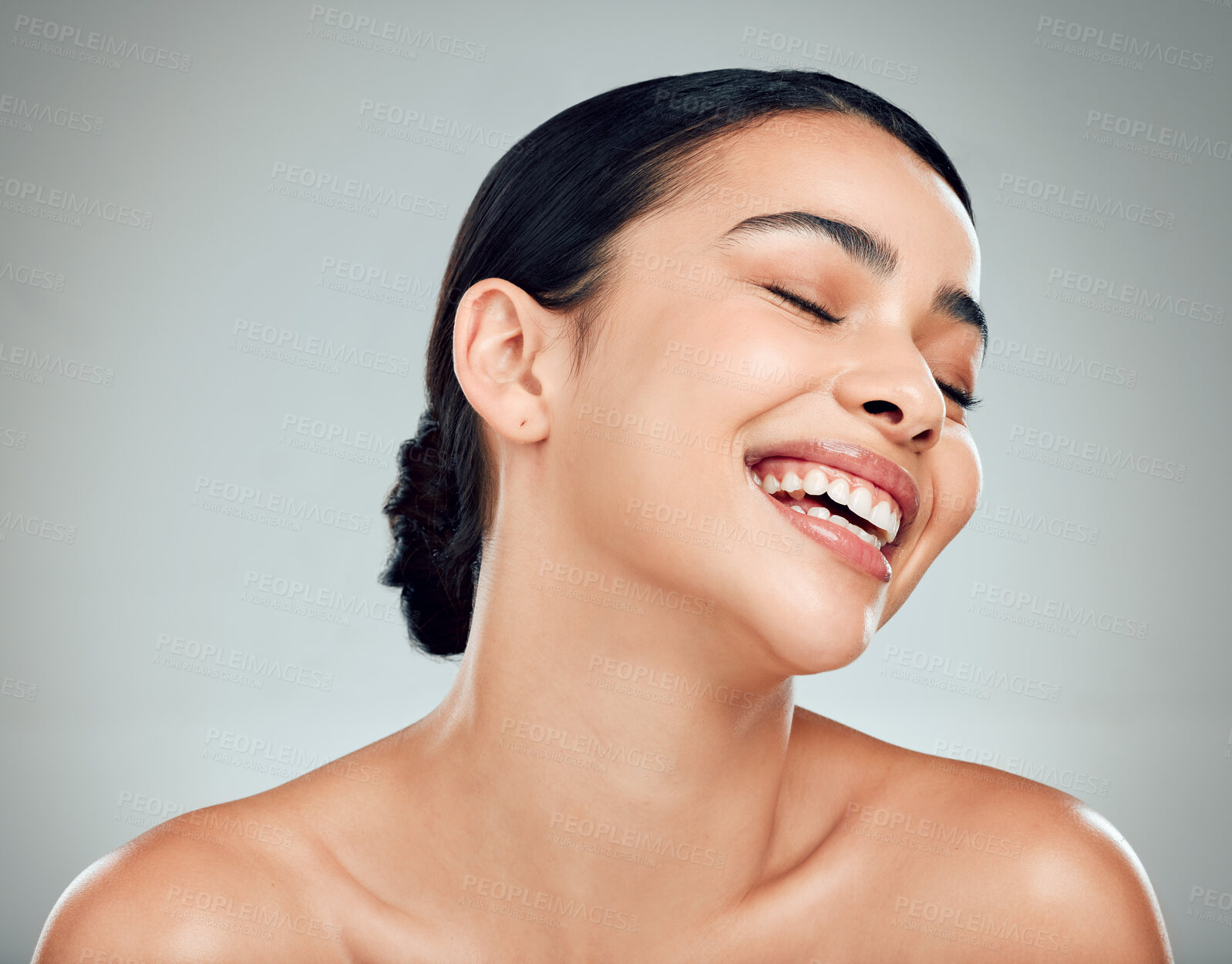 Buy stock photo A beautiful young mixed race woman with glowing skin posing against grey copyspace background. Hispanic woman with natural looking eyelash extensions smiling while feeling her smooth skin in a studio