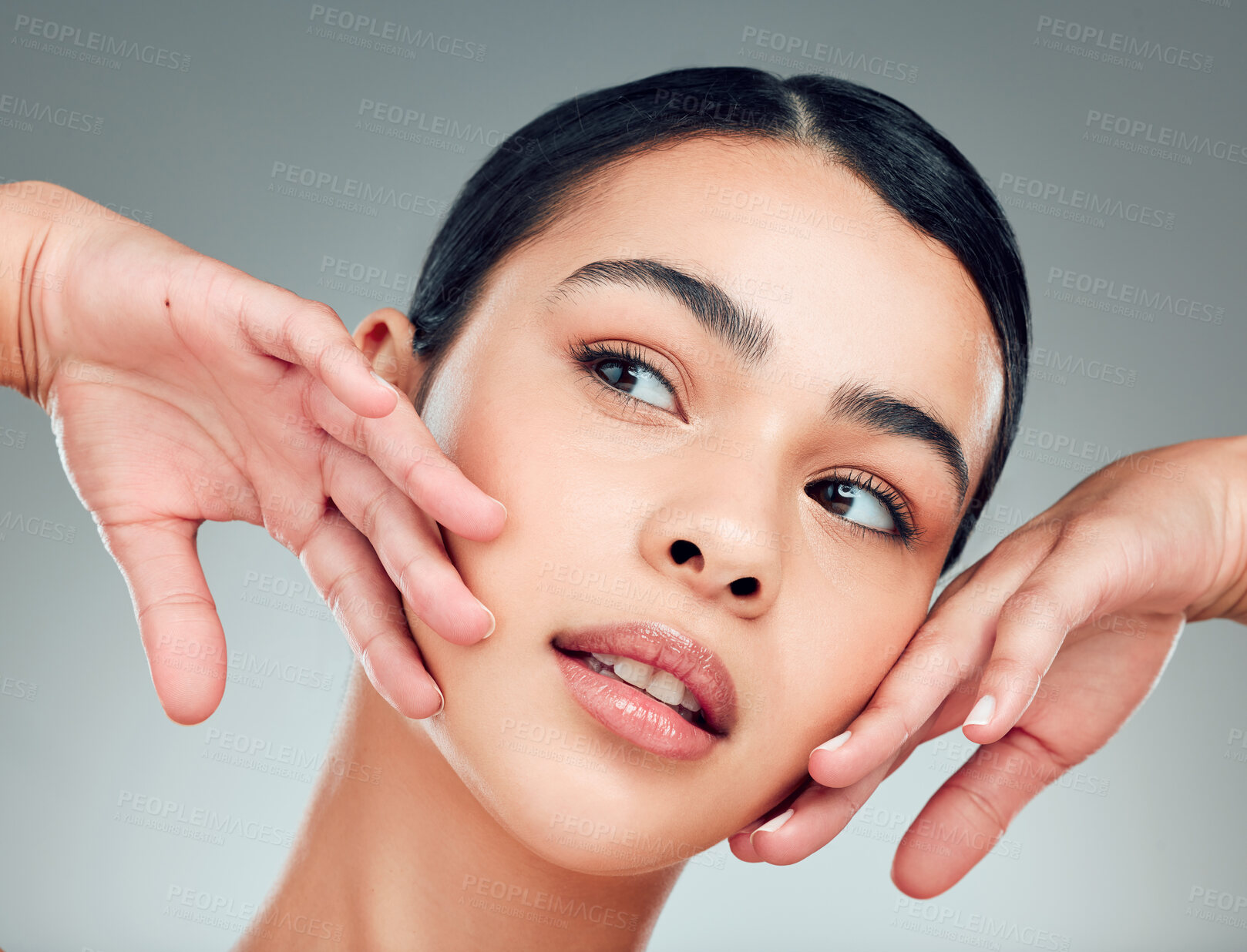 Buy stock photo A beautiful young mixed race woman with glowing skin posing against grey copyspace background. Hispanic woman with natural looking eyelash extensions smiling while feeling her smooth skin in a studio