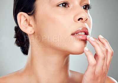 Buy stock photo Closeup of a beautiful young mixed race woman with glowing skin posing against gree copyspace background. Hispanic woman applying lipgloss in a studio