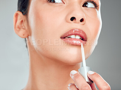 Buy stock photo A beautiful young mixed race woman with glowing skin posing against grey copyspace background. Hispanic woman applying lipstick in a studio