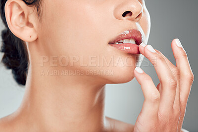 Buy stock photo Closeup of a beautiful young mixed race woman with glowing skin posing against grey copyspace background. Hispanic woman applying lipgloss in a studio