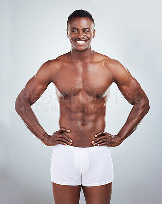 Buy stock photo Portrait of a smiling African American fitness model posing topless in a underwear and looking muscular. Happy black male athlete isolated on grey copyspace in a studio wearing boxers