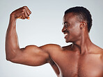 Closeup of one African American fitness model posing topless in and looking muscular. Confident black male athlete isolated on grey copyspace in a studio flexing his bicep