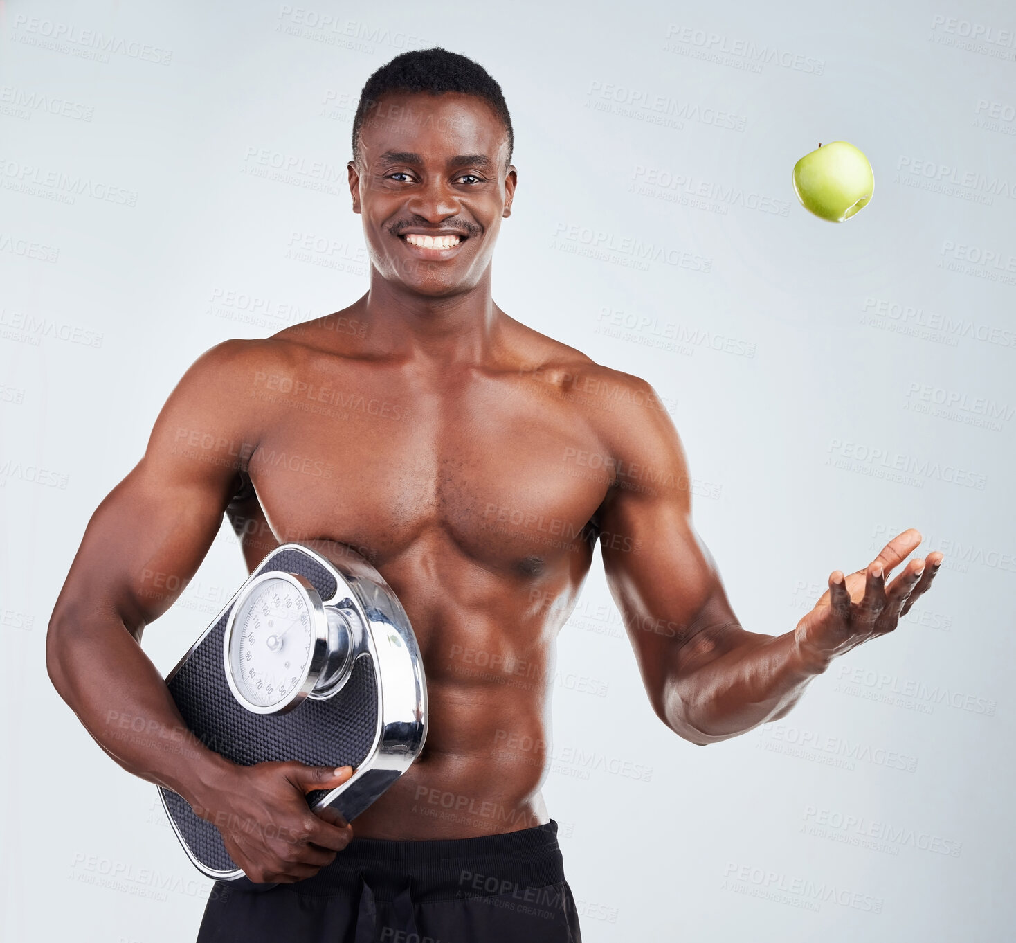 Buy stock photo Portrait of a smiling African American fitness model posing topless with an apple and a scale. Happy black male athlete isolated on grey copyspace positive about his healthy diet