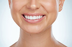 Closeup of unknown woman smiling with white teeth after a whitening treatment. Happy caucasian model isolated against grey background in a studio and showing perfect dental hygiene routine and care