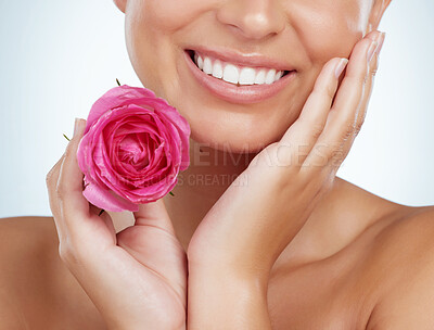 Buy stock photo Smiling unknown woman holding pink rose while posing topless and touching face. Caucasian model isolated against grey studio background with smooth glowing skin and delicate healthy skincare routine