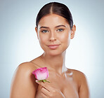 Portrait of beautiful woman holding pink rose while posing topless with copyspace. Caucasian model isolated against grey studio background with smooth glowing skin, delicate healthy skincare routine