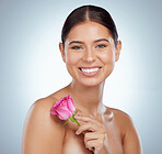 Portrait of smiling woman holding pink rose while posing topless with copyspace. Caucasian model isolated against grey studio background with smooth glowing skin, delicate healthy skincare routine