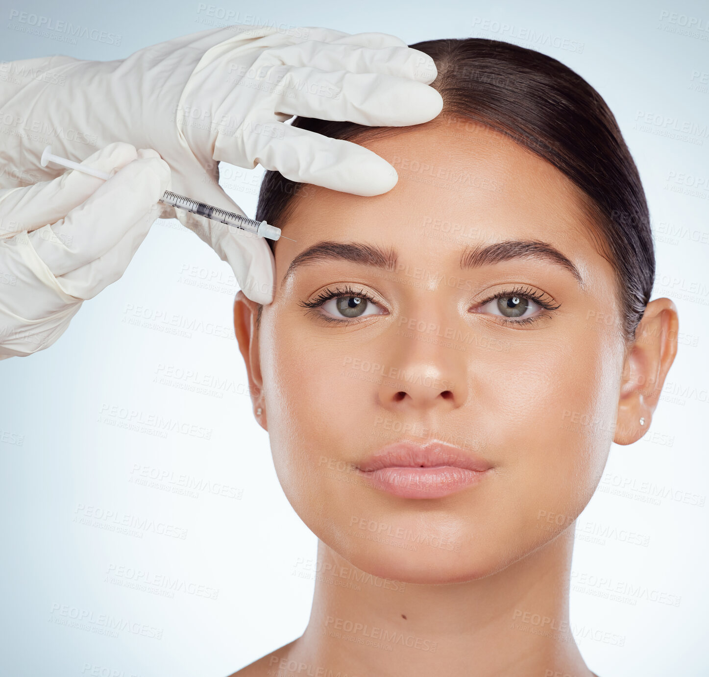 Buy stock photo Closeup portrait of woman getting facial fillers or botox. Young caucasian model isolated against a grey studio background with copyspace. Dermatologist injecting patient during cosmetic procedure