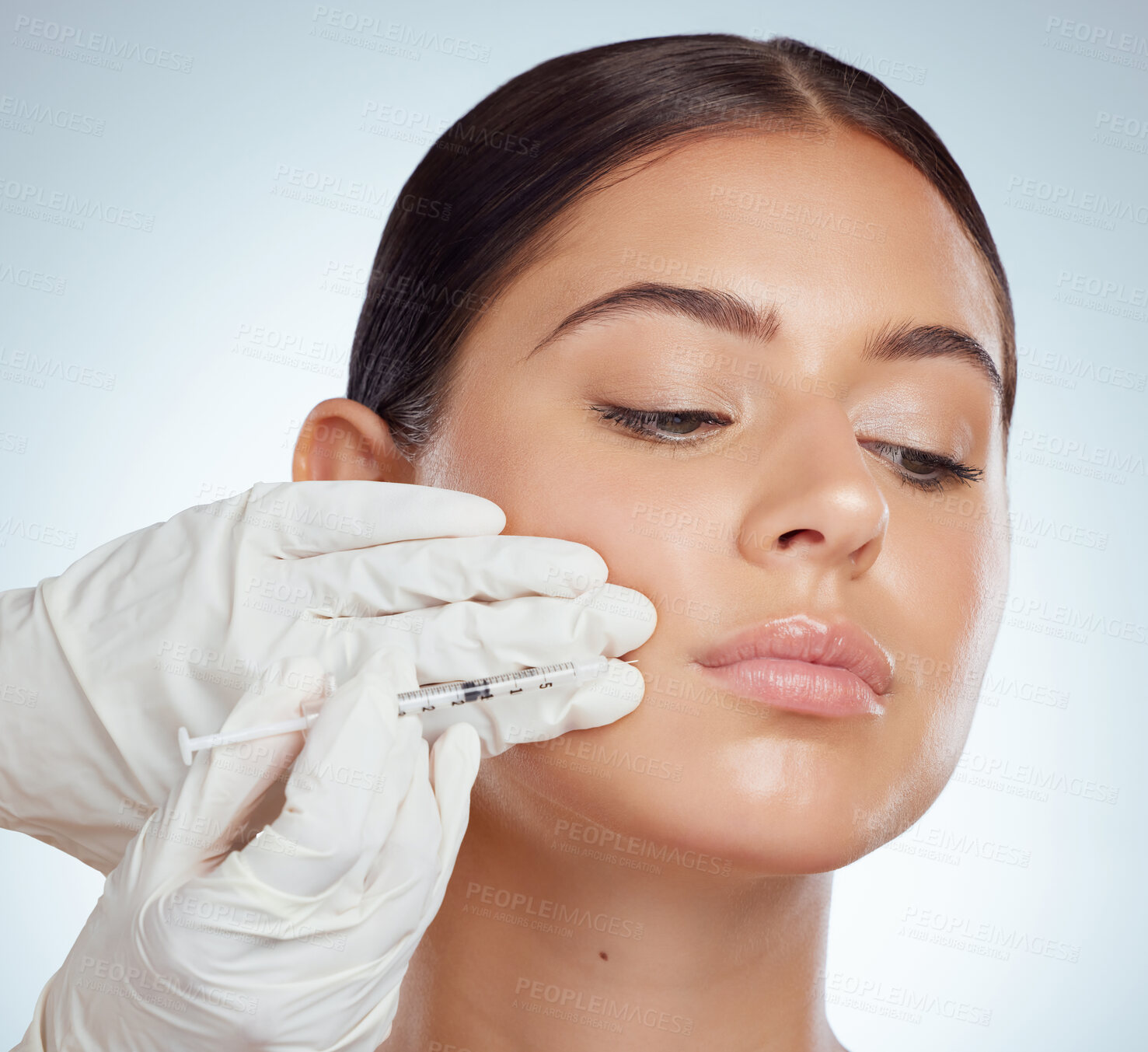 Buy stock photo Closeup of woman getting lip fillers or botox. Young caucasian model isolated against a grey studio background with copyspace. Dermatologist injecting patient during anti ageing cosmetic procedure