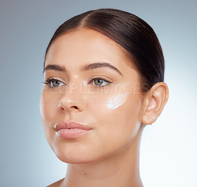 Buy stock photo Closeup of beautiful woman with face cream on her cheek posing with copyspace. Caucasian model isolated against grey studio background with product. Moisturise and sunscreen for healthy skincare