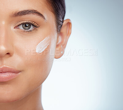 Buy stock photo Closeup portrait beautiful woman with face cream on her cheek posing with copyspace. Caucasian model isolated against grey studio background with product. Moisturise and sunscreen for healthy skincare