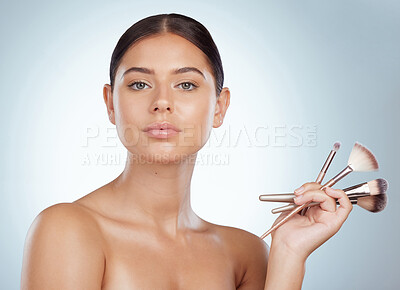 Buy stock photo Portrait of beautiful woman holding cosmetic makeup brushes while posing with copyspace. Caucasian model isolated against a grey studio background. Getting ready to apply makeup in skincare routine
