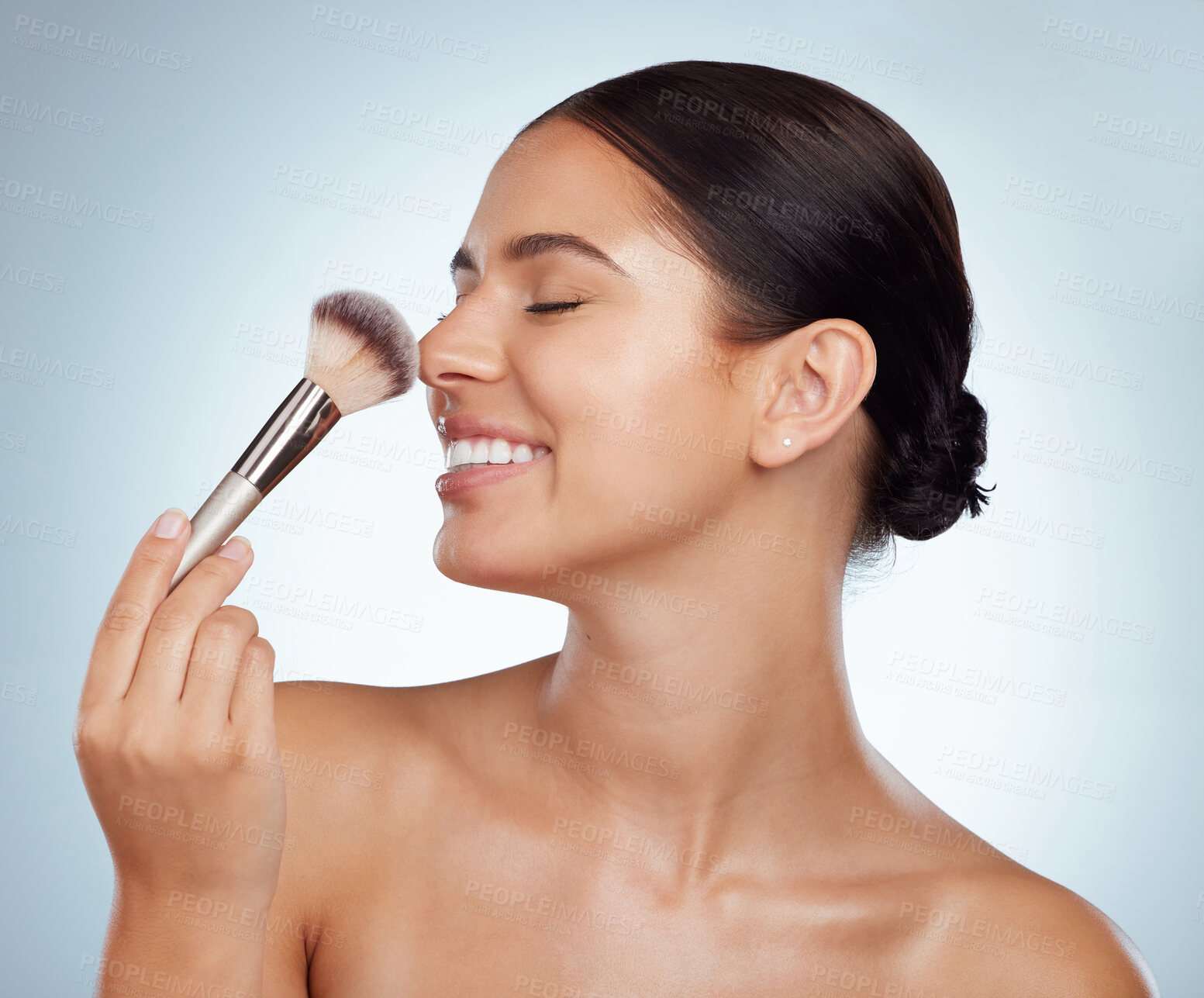 Buy stock photo Beautiful woman holding and using cosmetic makeup brush to apply blush makeup while posing with copyspace. Caucasian model isolated against grey studio background. Getting ready after skincare routine