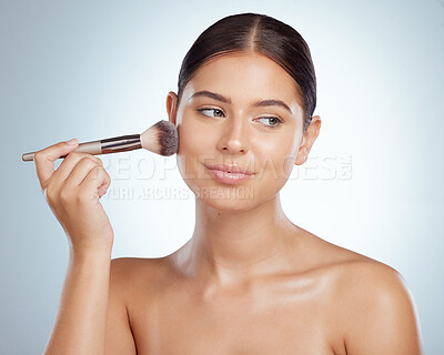 Buy stock photo Beautiful woman holding and using cosmetic makeup brush to apply blush makeup while posing with copyspace. Caucasian model isolated against grey studio background. Getting ready after skincare routine