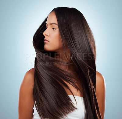 A hispanic brunette woman with long lush beautiful hair posing against a grey studio background. Mixed race female standing showing her beautiful healthy hair