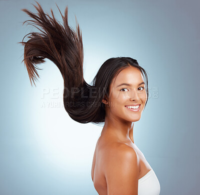 Portrait of a hispanic brunette woman with long lush beautiful hair smiling and posing against a grey studio background. Mixed race female standing showing her beautiful healthy hair