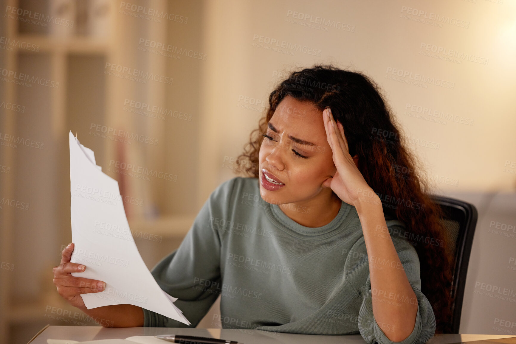 Buy stock photo Young woman looking stressed while going through paperwork alone in an office at night. One female only looking worried while struggling with her budget and finances. Burnout from deadlines