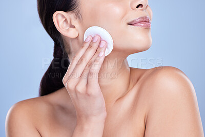 Buy stock photo A beautiful smiling mixed race woman using a cotton pad to remove makeup during a selfcare grooming routine. Hispanic woman applying cleanser to her face against blue copyspace background