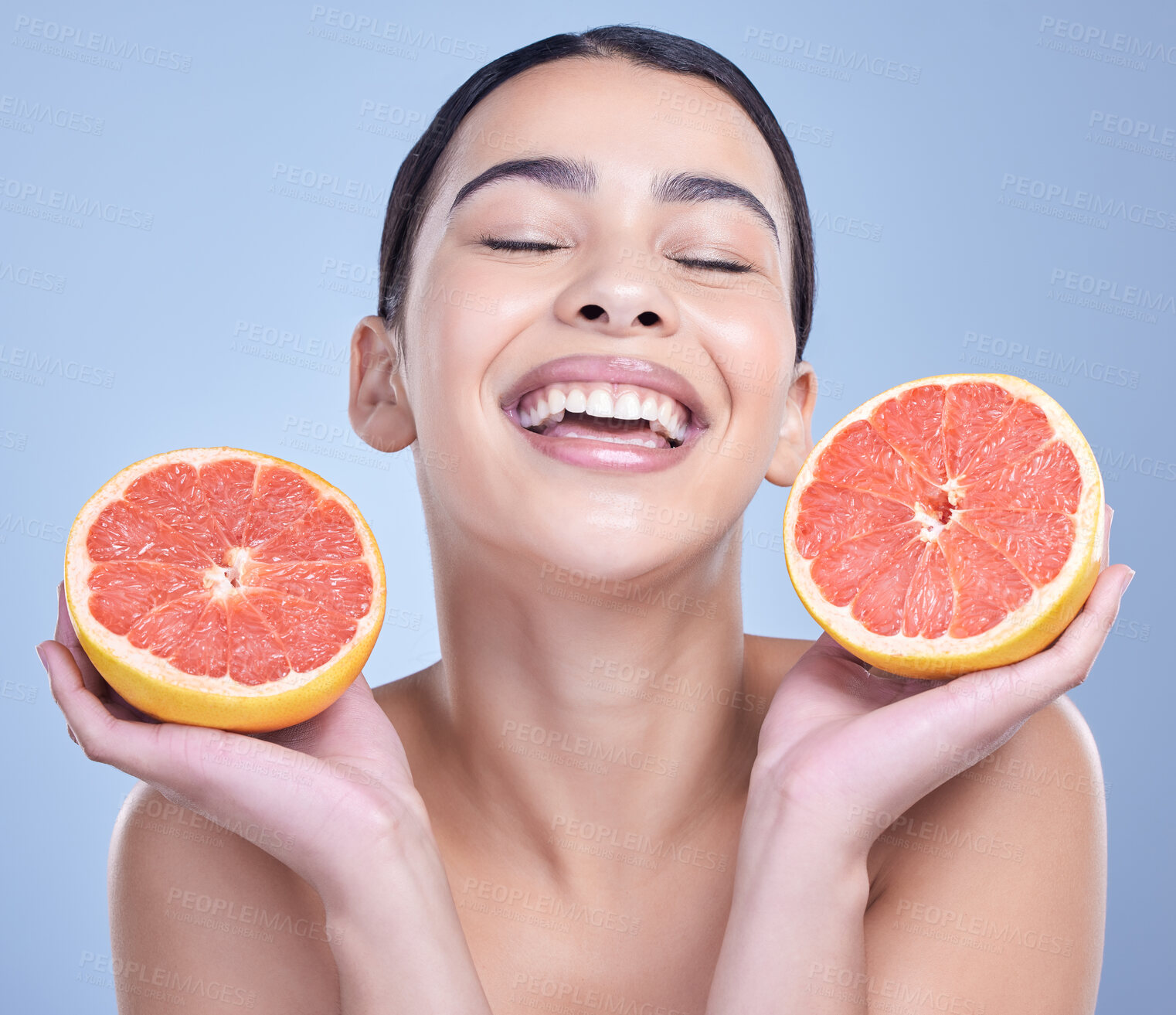 Buy stock photo A  happy mixed race woman holding a grapefruit. Hispanic model promoting the skin benefits of citrus diet against a blue copyspace background
