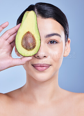 Buy stock photo Studio Portrait of a happy smiling mixed race woman holding an avocado. Hispanic model promoting the skin benefits of a healthy diet against a blue copyspace background