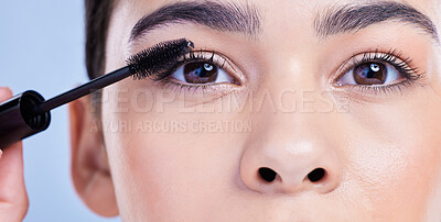 Closeup portrait of a beautiful young mixed race woman with glowing skin posing against blue copyspace background. Hispanic woman with natural looking eyelash extensions applying mascara
